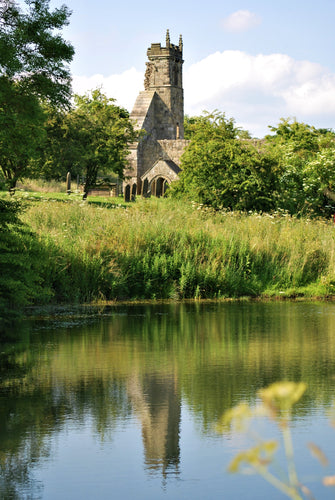 A ruined medieval church reflected in a lake.