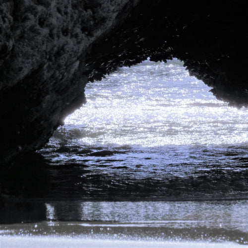 A sea cave with the sea glistening within.