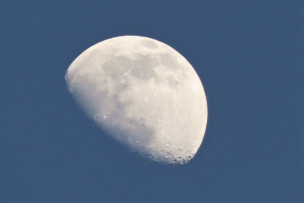 The moon shining in a blue sky.